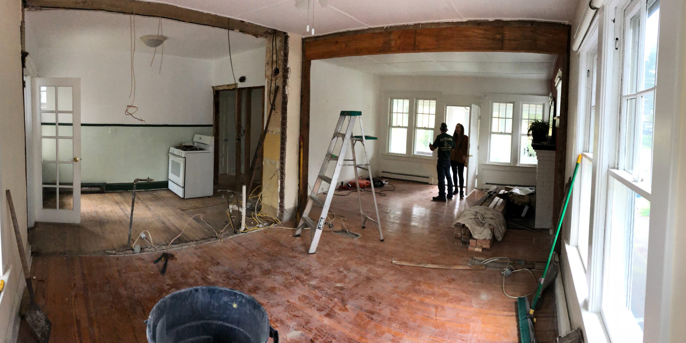 The main floor during demolition: ladder, exposed beam, the old kitchen still standing at the left.