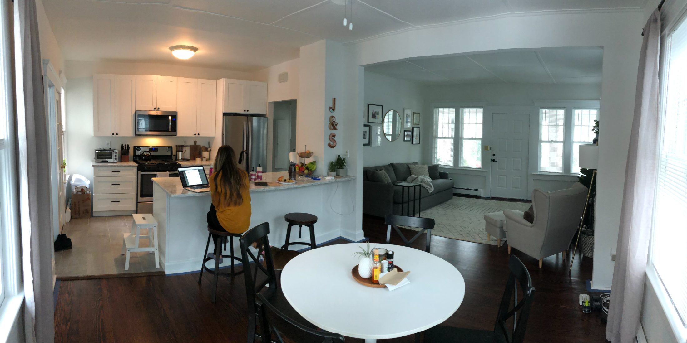The same view finished and furnished, with Steph working at the peninsula.