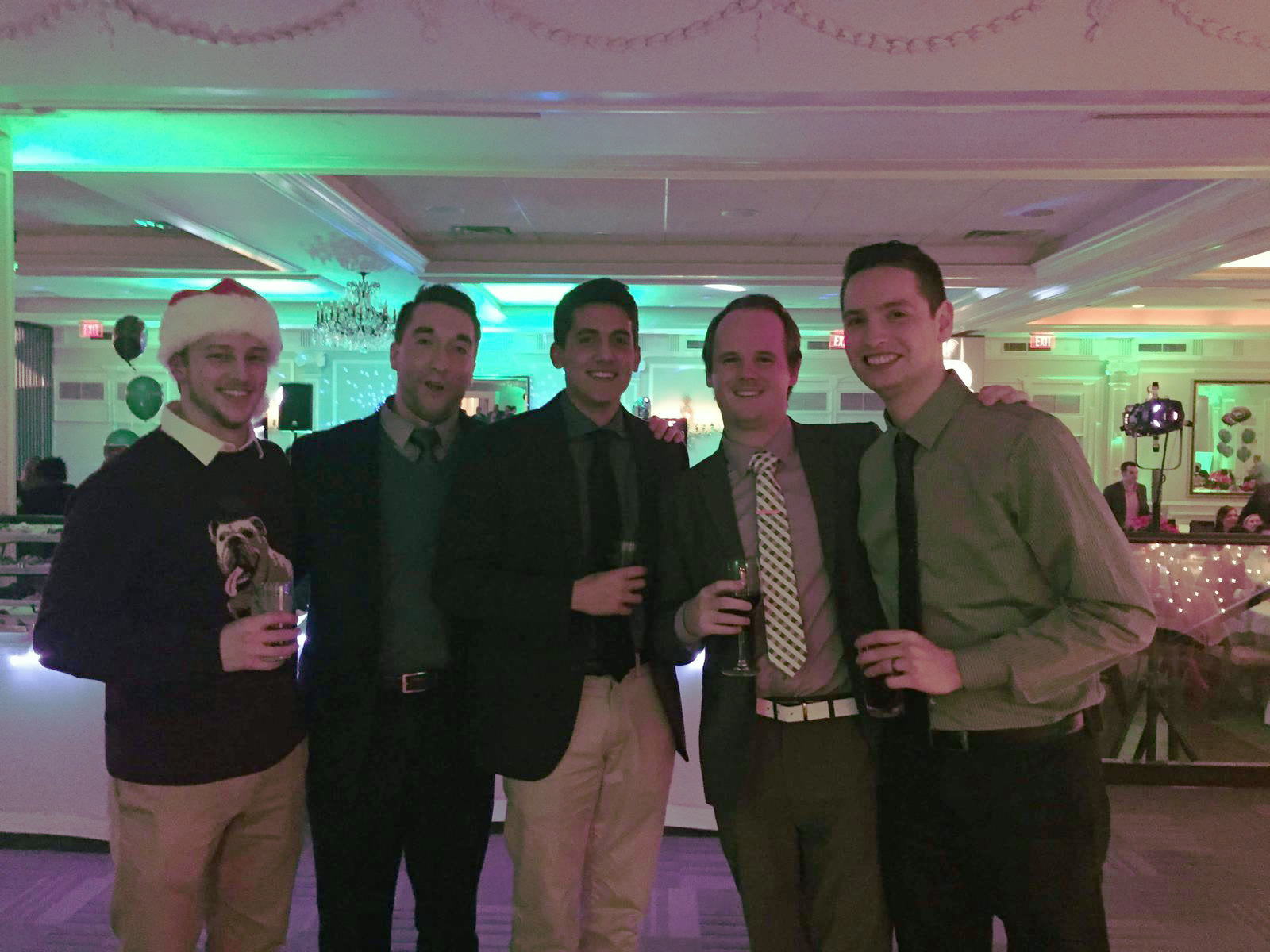 Five members of the Jets media team at a holiday party, lit green.