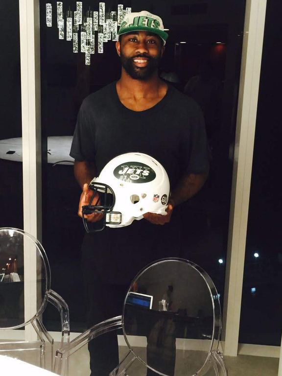 Darrelle Revis holding a New York Jets helmet and wearing a Jets cap, photographed by Justin Herrera.